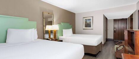 Quarto de hotel com duas camas, uma mesa de cabeceira com abajur, cômoda de madeira e um quadro na parede.