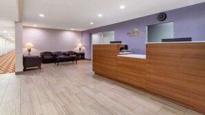 A hotel reception area with a wooden reception desk, two leather sofas, and a clock on the wall. - Microtel Inn & Suites by Wyndham Philadelphia Airport (Philadelphia)