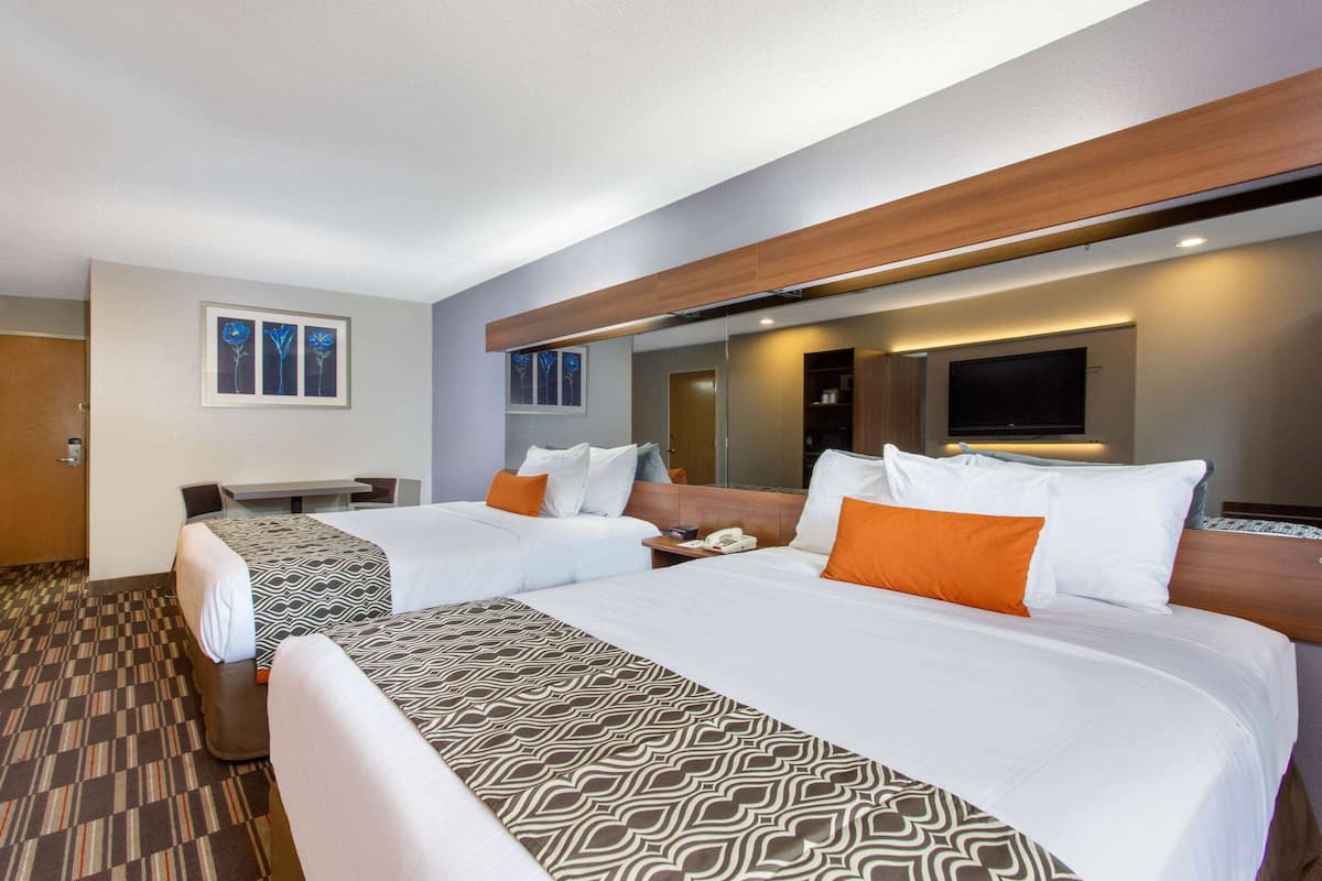 A hotel room with two beds, a desk, and a TV.