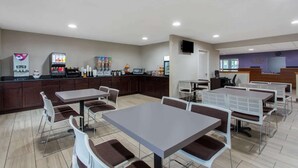 A modern cafeteria with multiple tables and chairs, a coffee machine, and a refrigerator stocked with beverages. - Microtel Inn & Suites by Wyndham Philadelphia Airport (Philadelphia)