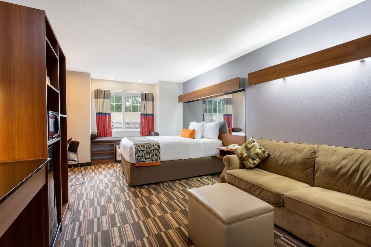 A hotel room with a bed, a sofa, a desk, and a wardrobe.