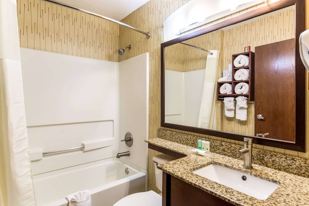 A bathroom with a bathtub, a sink, and a mirror.