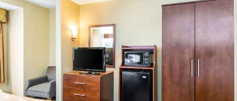 Habitación de hotel con cama, cómoda, televisor, microondas, silla y armario.