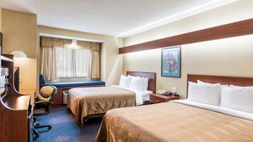A hotel room with two beds, a desk, a chair, a window with curtains, and a painting on the wall.