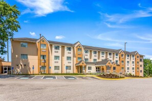 A multi-story hotel with a beige facade, multiple windows, and a parking lot in front. - Quality Inn Chester - South Richmond (Chester)