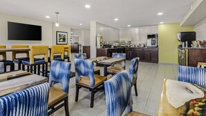 A modern dining area with striped chairs and a flat-screen TV. - Clarion Pointe Staunton East (Staunton)