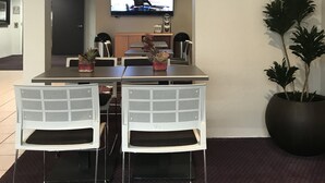 A conference room with a table, chairs, a television, and a potted plant. - Microtel Inn & Suites by Wyndham Morgan Hill/San Jose Area (Morgan Hill)