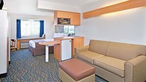 A compact room with a kitchenette, a sofa, a small table, and a window with curtains. - Microtel Inn & Suites by Wyndham Morgan Hill/San Jose Area (Morgan Hill)