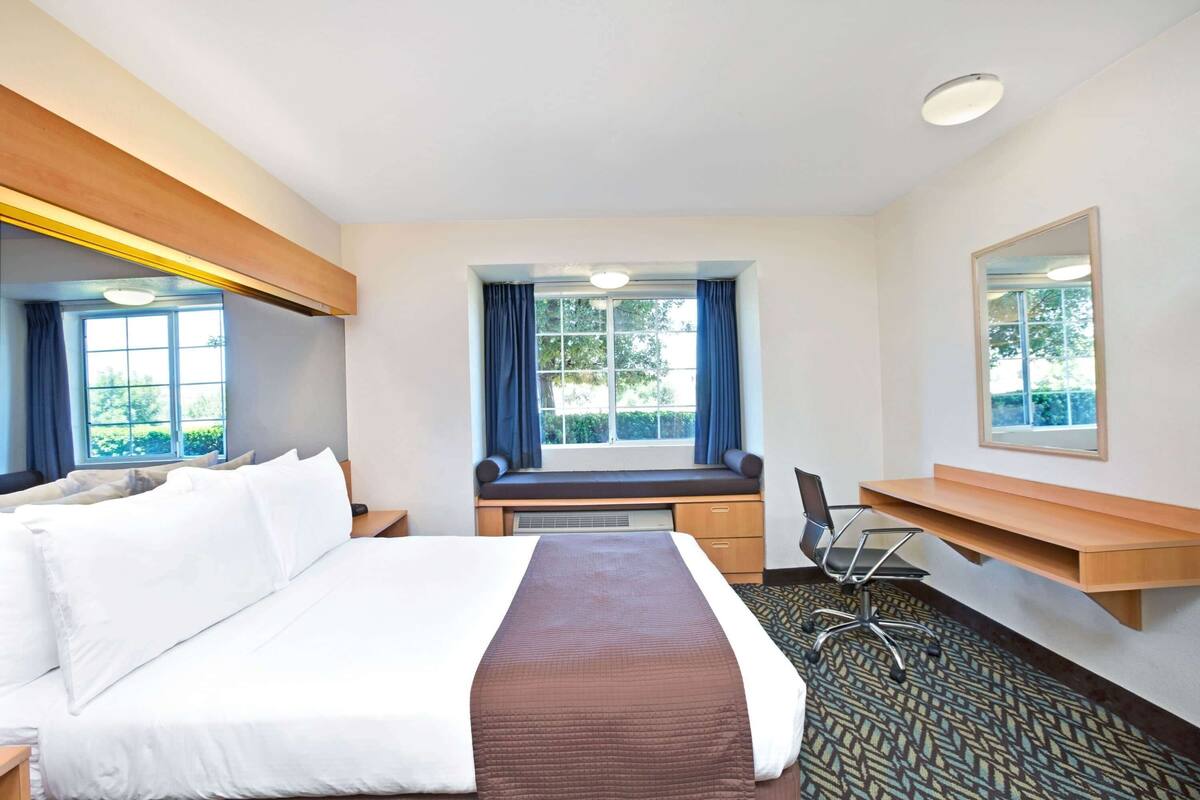 Une chambre d’hôtel équipée d’un lit, d’un bureau, d’une chaise et de grandes fenêtres.