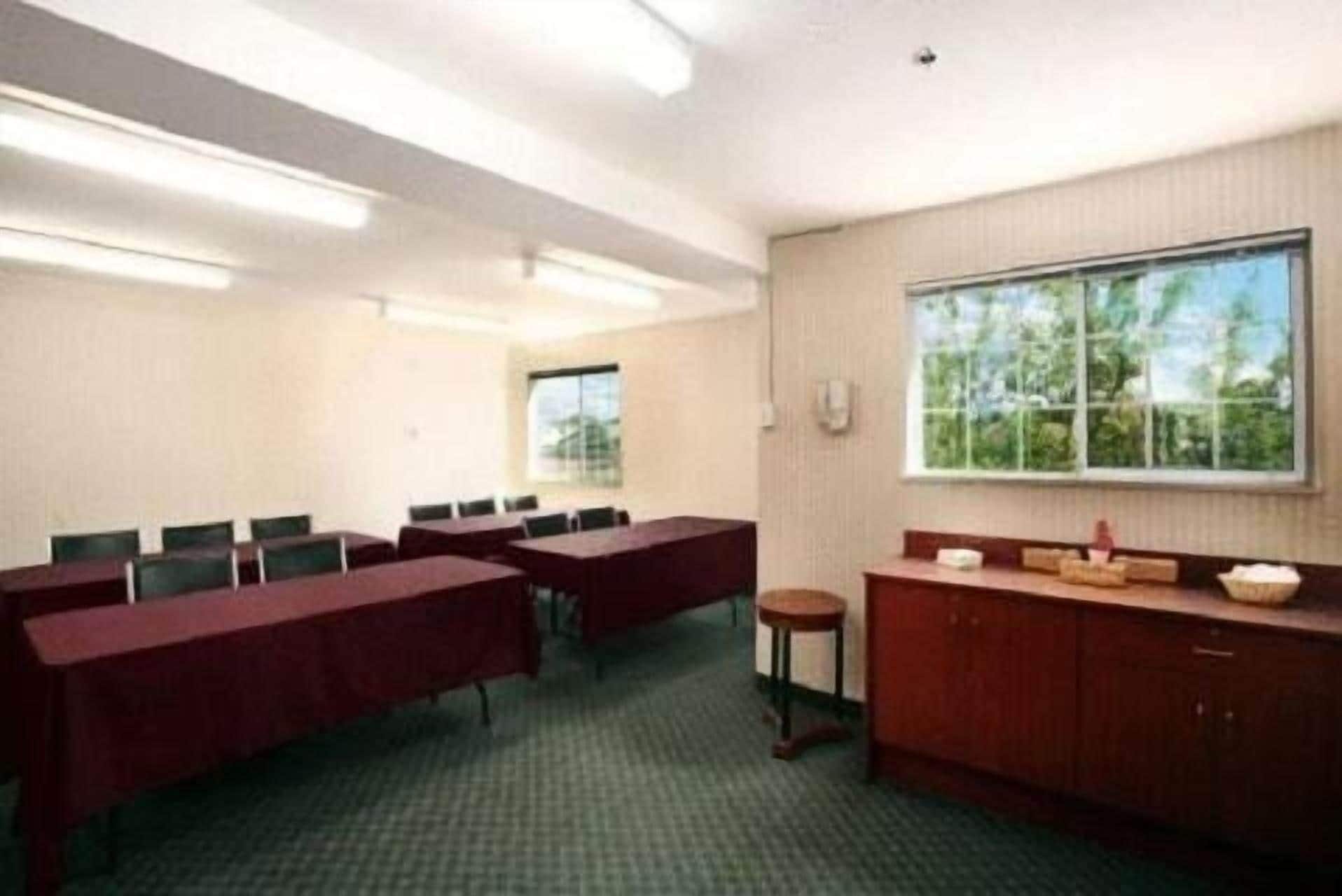 A conference room with tables and chairs, a window with a view, and a small stool.