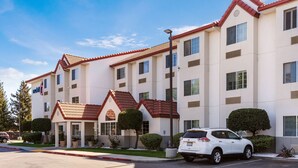 Ein mehrgeschossiges Hotel mit rotem Ziegeldach, zahlreichen Fenstern und einem Parkplatz.