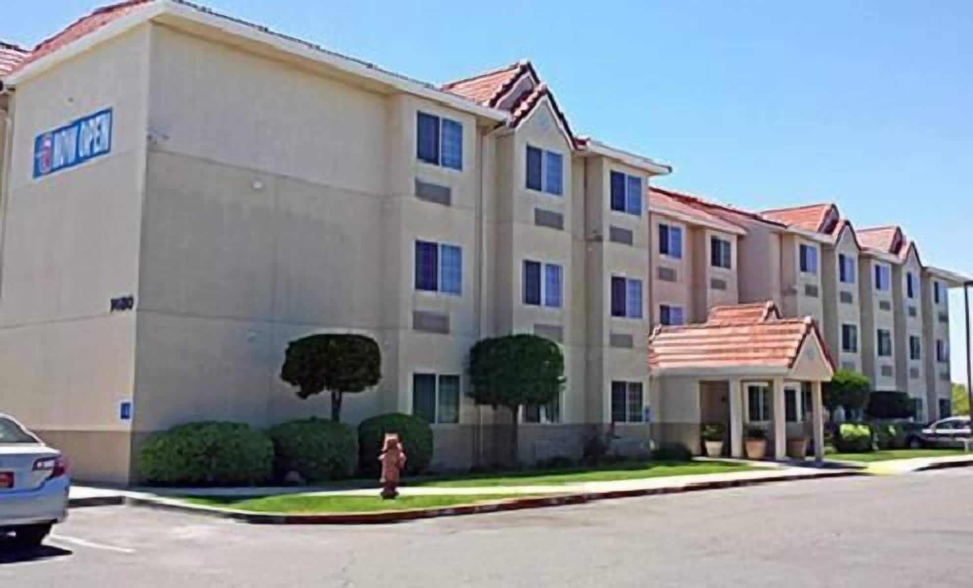 A multi-story hotel with a beige facade, multiple windows, and a red-tiled roof.