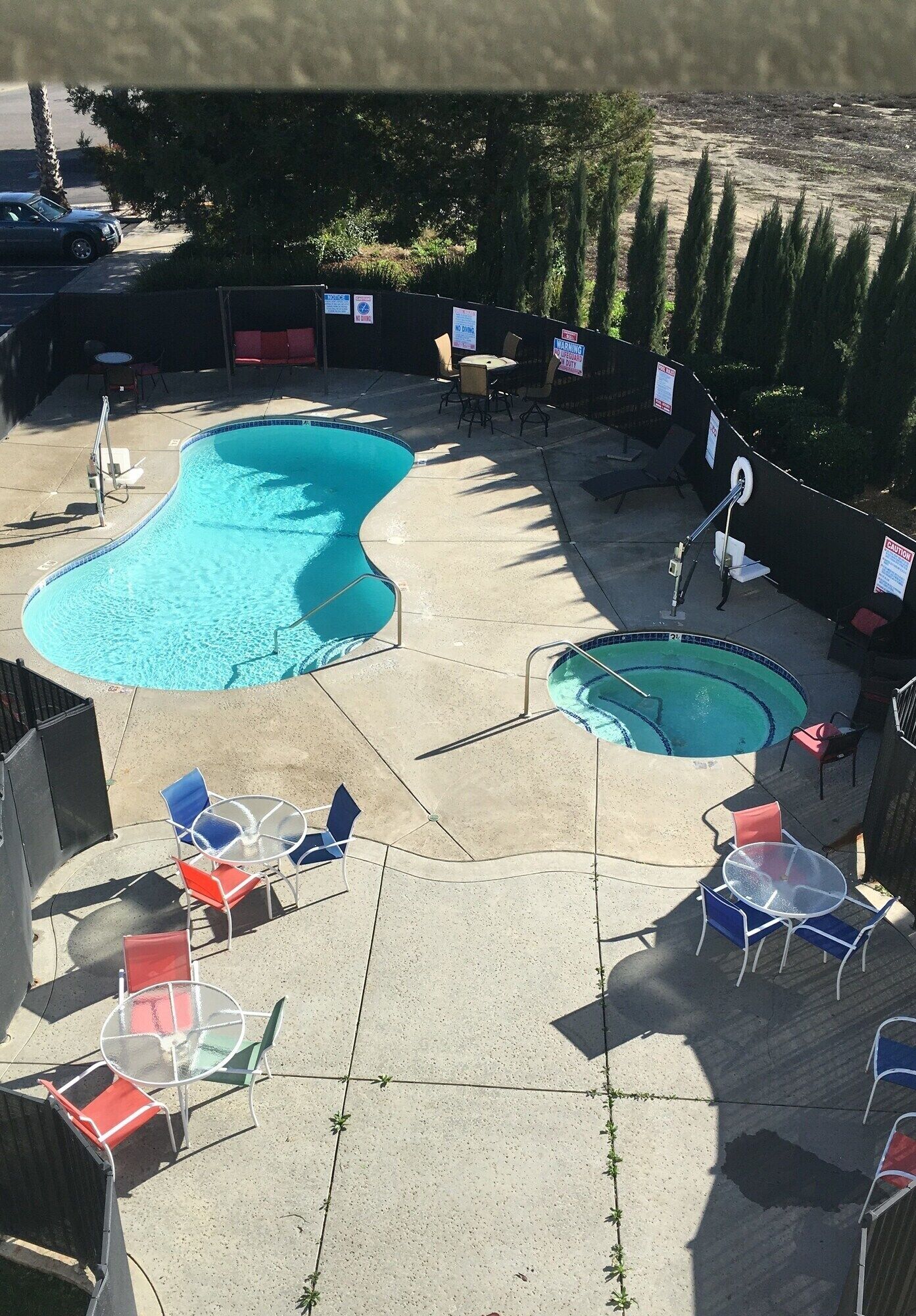 Un área de piscina con dos piscinas, rodeada de sillones y mesas.