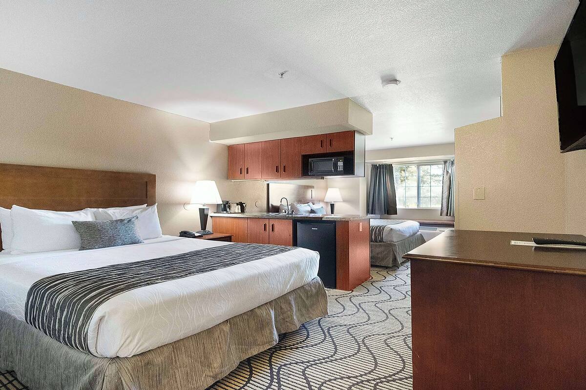 Een hotelkamer met een bed, een bureau, een kitchenette en een televisie.