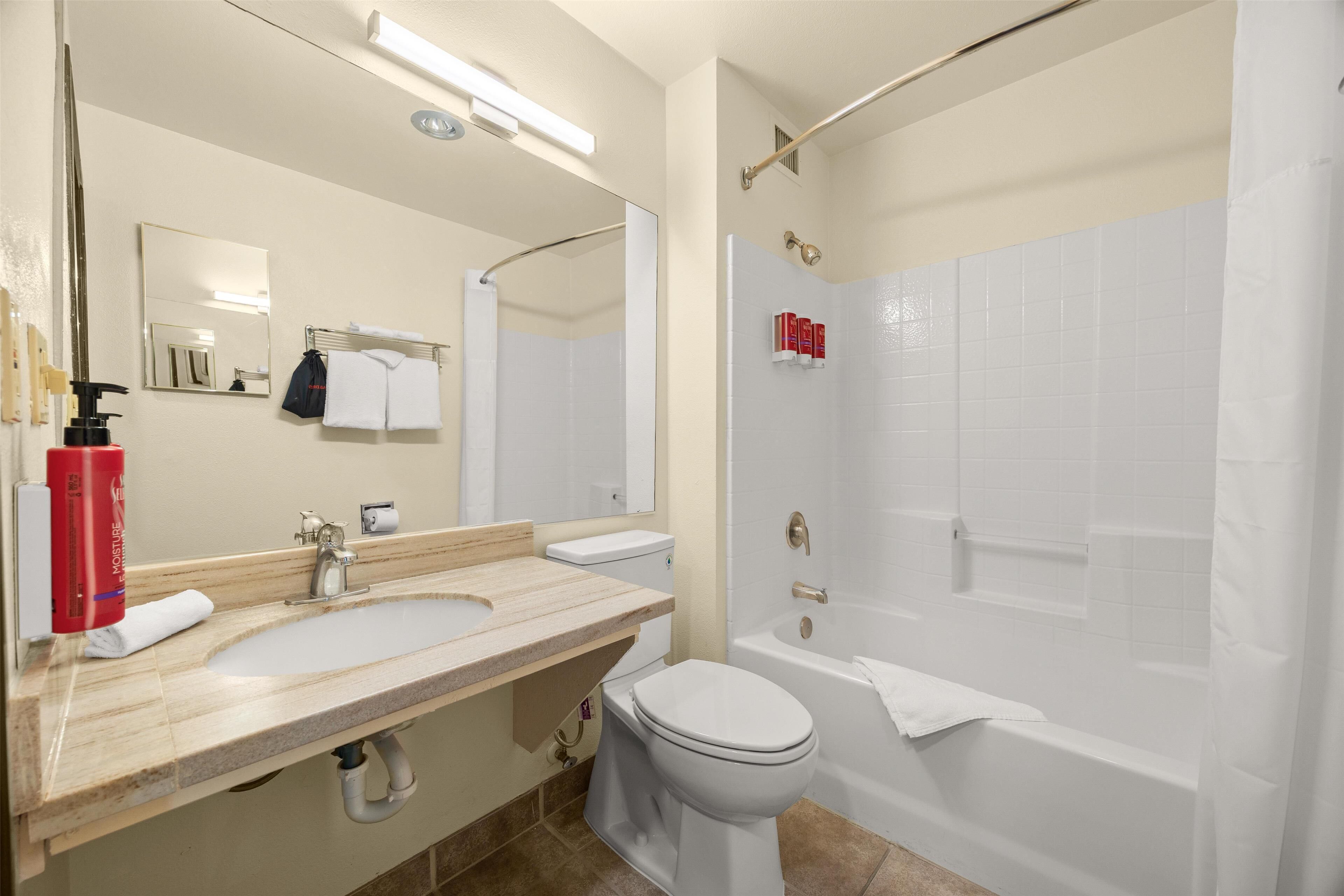 A modern bathroom with a sink, toilet, and bathtub.