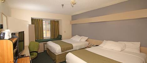 A hotel room with two beds, a desk, a chair, and a window with curtains.