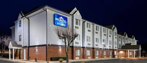 A Microtel hotel with a brick facade, multiple windows, and a parking lot.