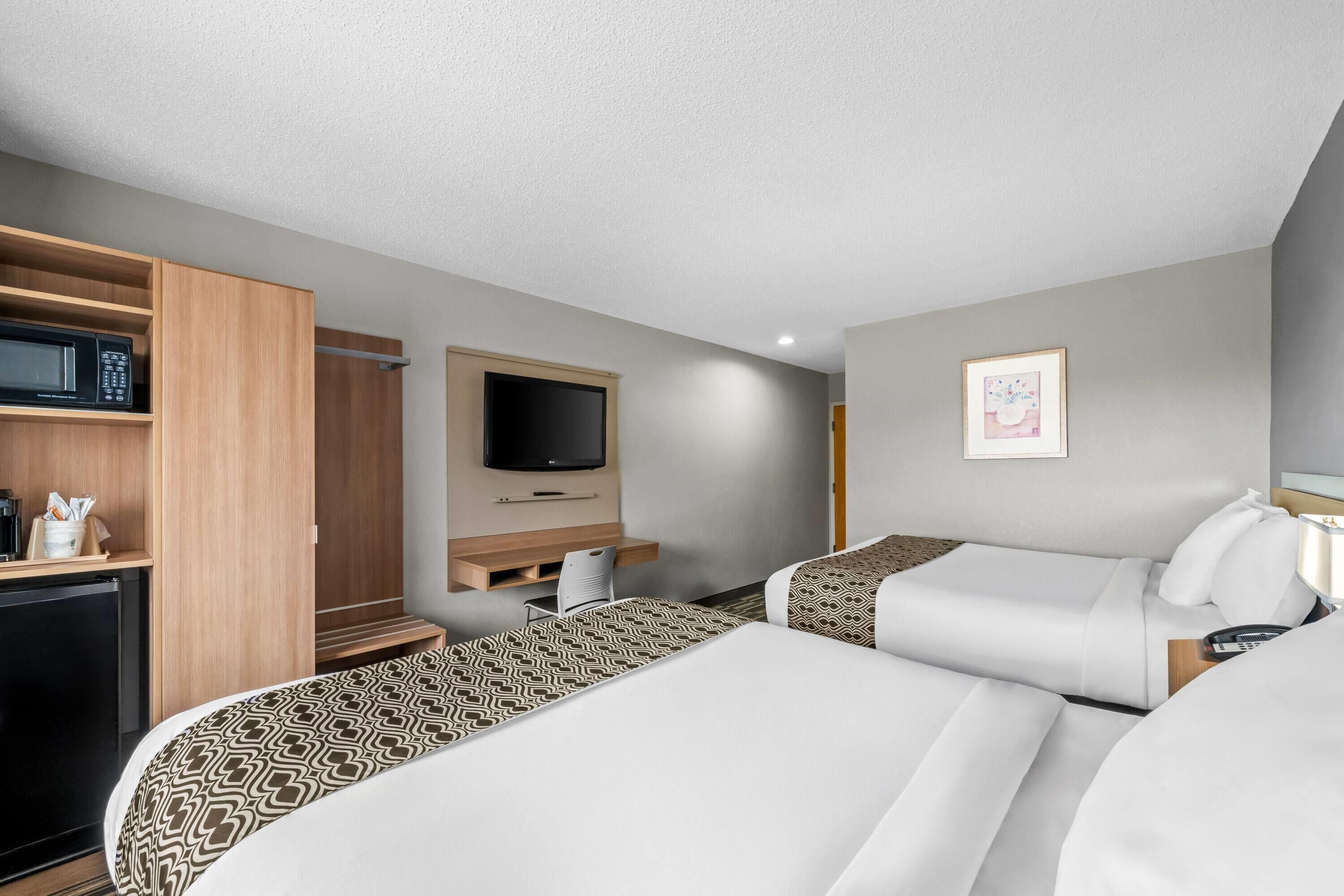 A hotel room with two beds, a desk, a television, and a wardrobe.