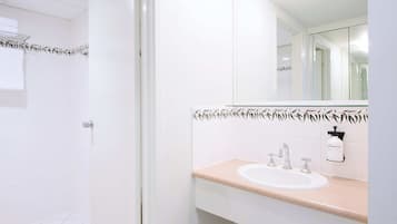 Un baño con lavamanos blanco, un espejo y un perchero para toallas.