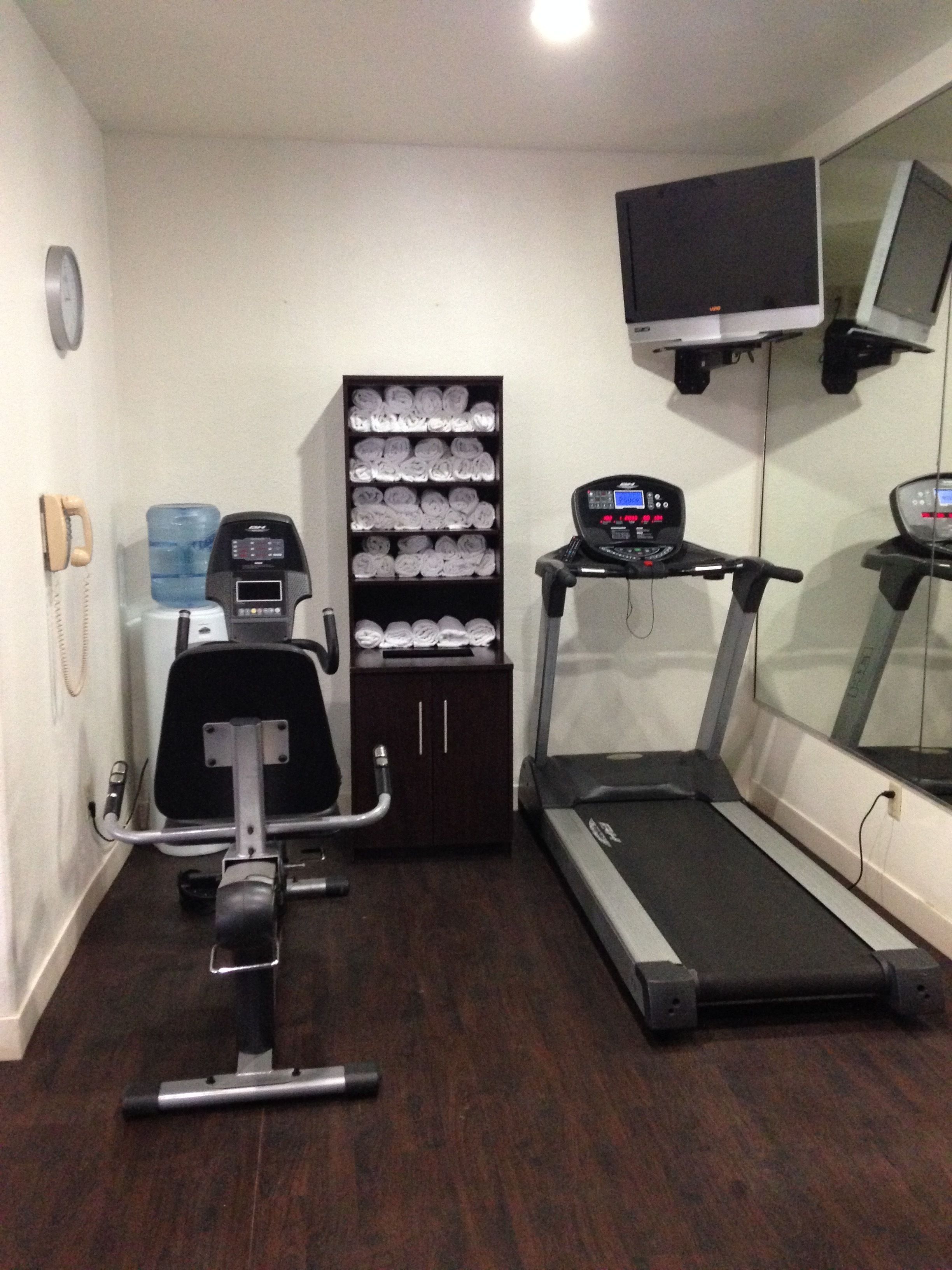 Een huisgym met een loopband, een hometrainer en een waterdispenser.