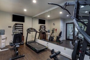 Ein Fitnessstudio mit Laufbändern, Krafttrainingsgeräten und einem Wasserspender.