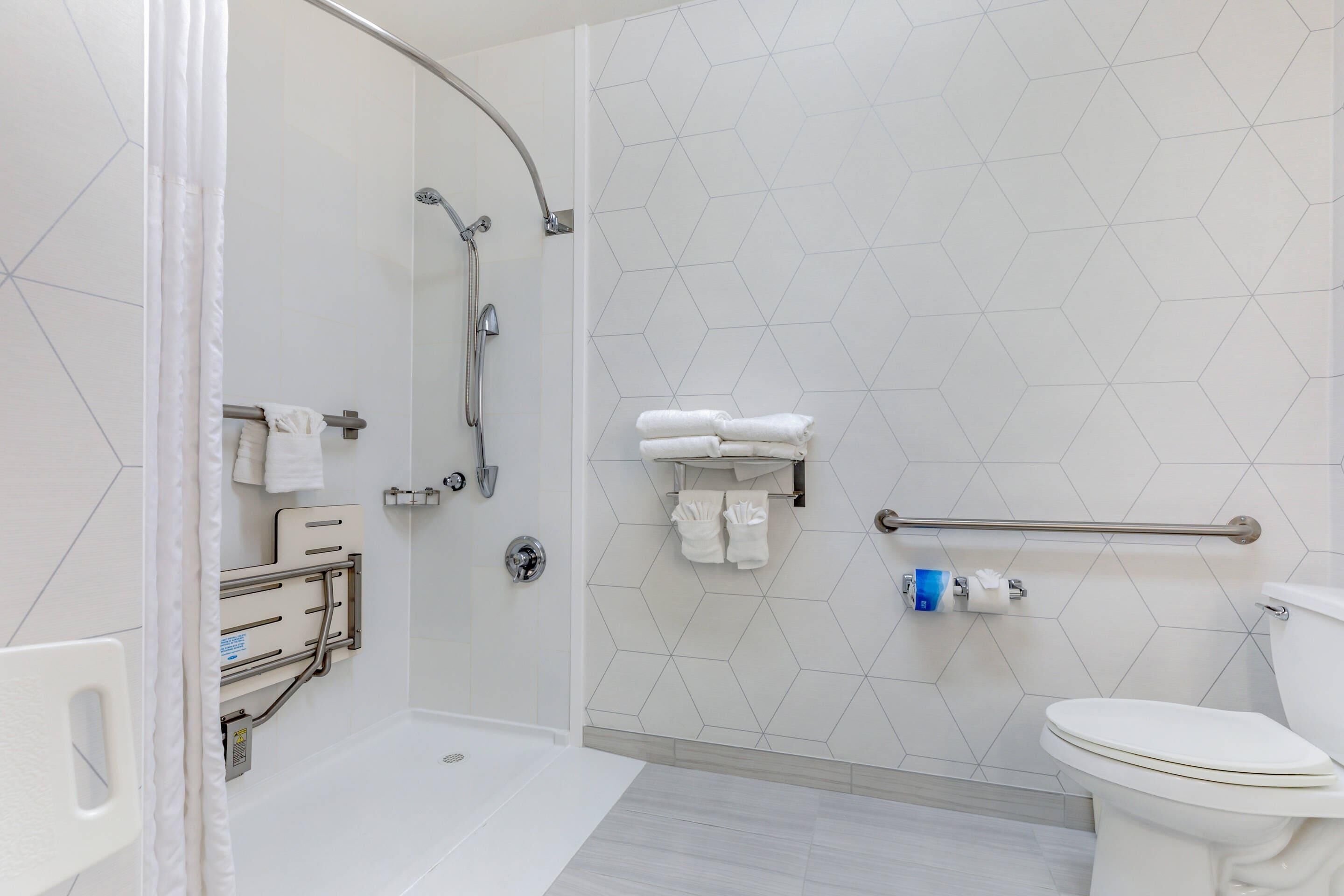 Un baño moderno con ducha, inodoro y barras de apoyo.