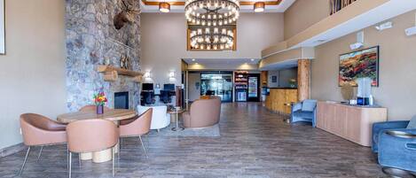 En rummelig lobby med stenvæg, lysekrone, receptionsdisk og siddeområde med et rundt bord og stole.