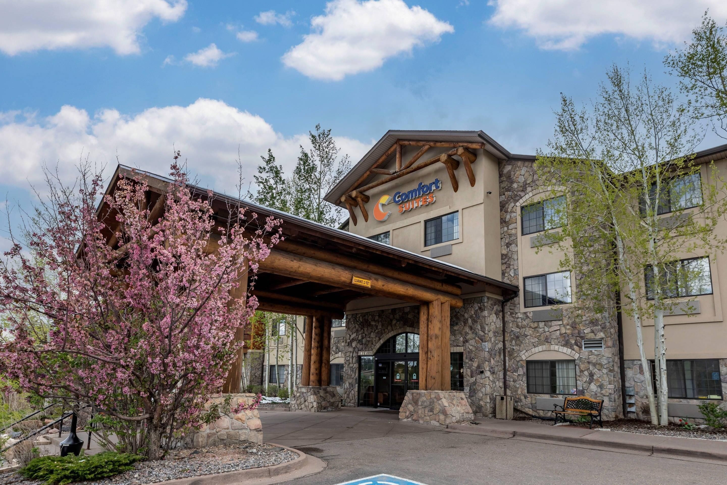 Un edificio con fachada de piedra, un acceso cubierto y un cartel que dice 'Comfort Suites'.