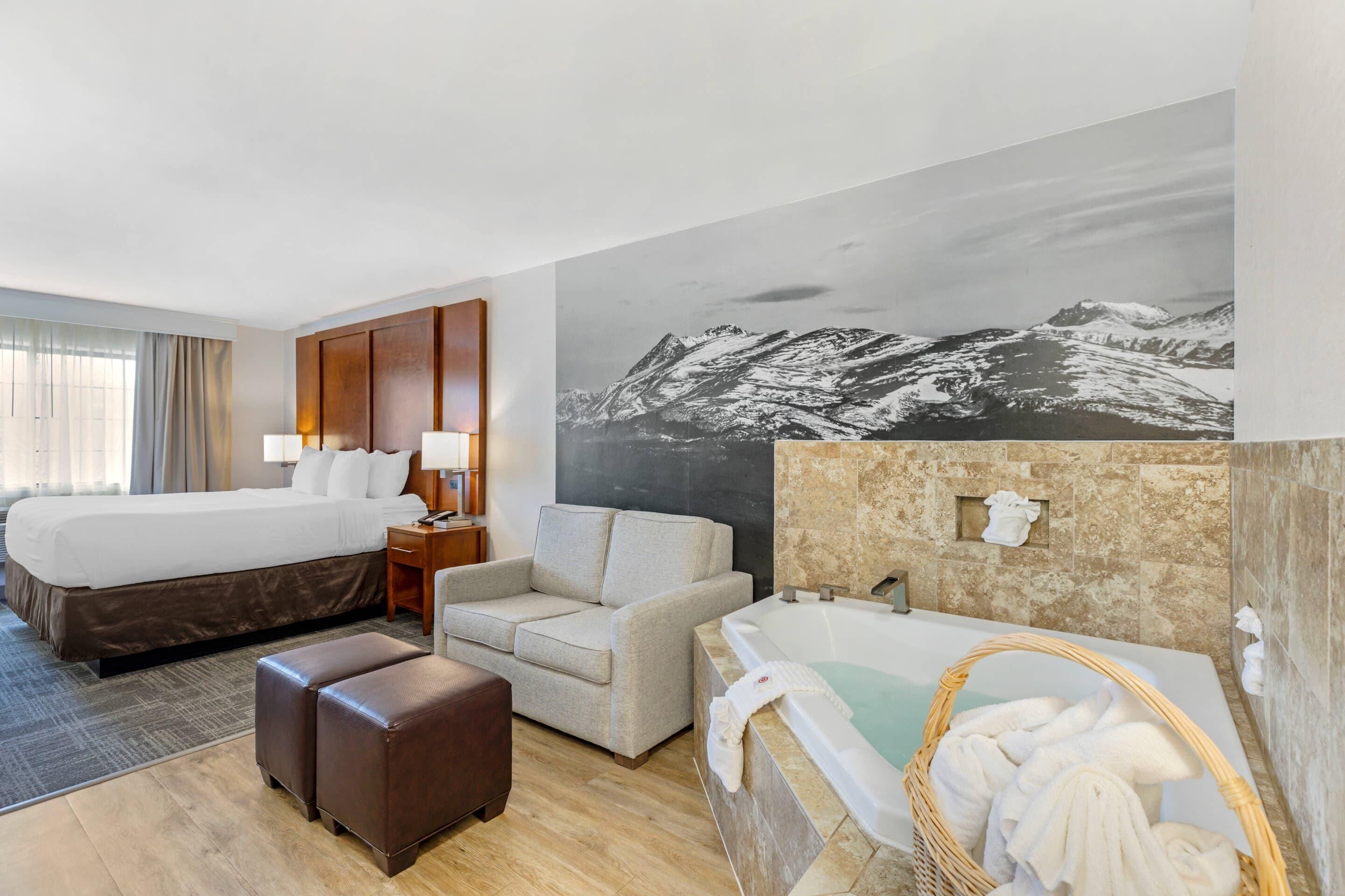 Habitación de hotel con cama, sofá, bañera y una pintura de una gran vista de montaña.