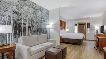 Habitación de hotel con sofá, cama, escritorio y un gran mural en la pared.