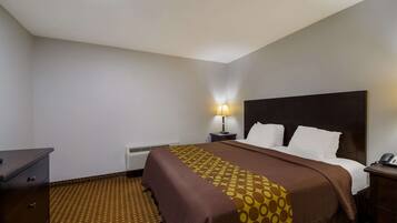 A hotel room with a bed, a desk, a lamp, and a telephone.