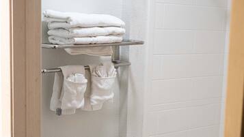 A bathroom with a toilet, a bathtub, and a towel rack with folded towels.