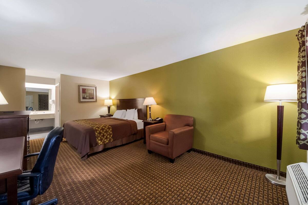 A hotel room with two beds, a desk, a chair, and a large window.