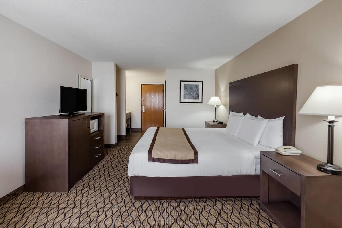 A hotel room with a bed, a desk with a lamp, a TV, and a wardrobe.