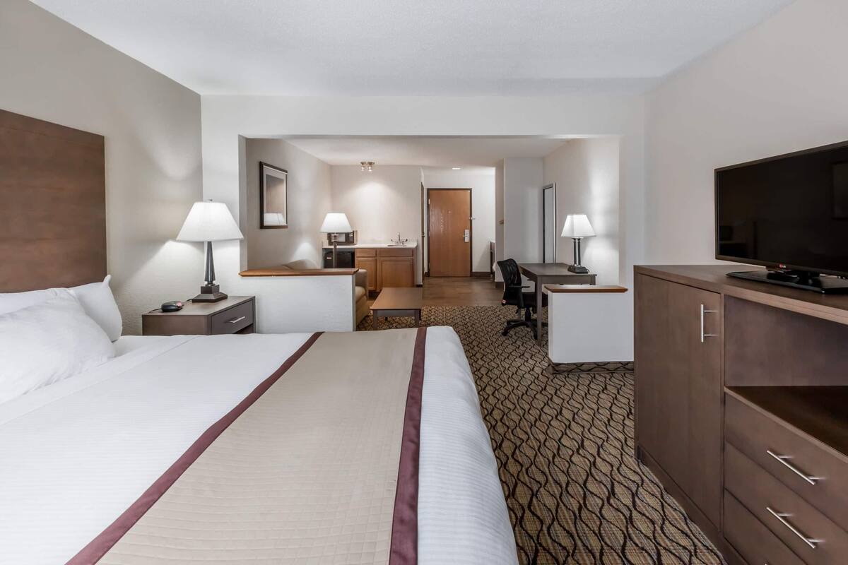 A hotel room with a large bed, a desk, a television, and a wardrobe.