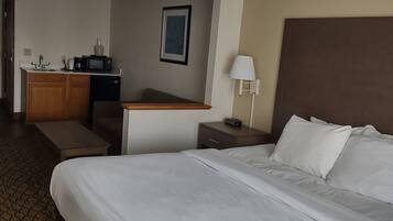 Une chambre d’hôtel avec un grand lit, un bureau avec un ordinateur, un four à micro-ondes et une petite kitchenette.