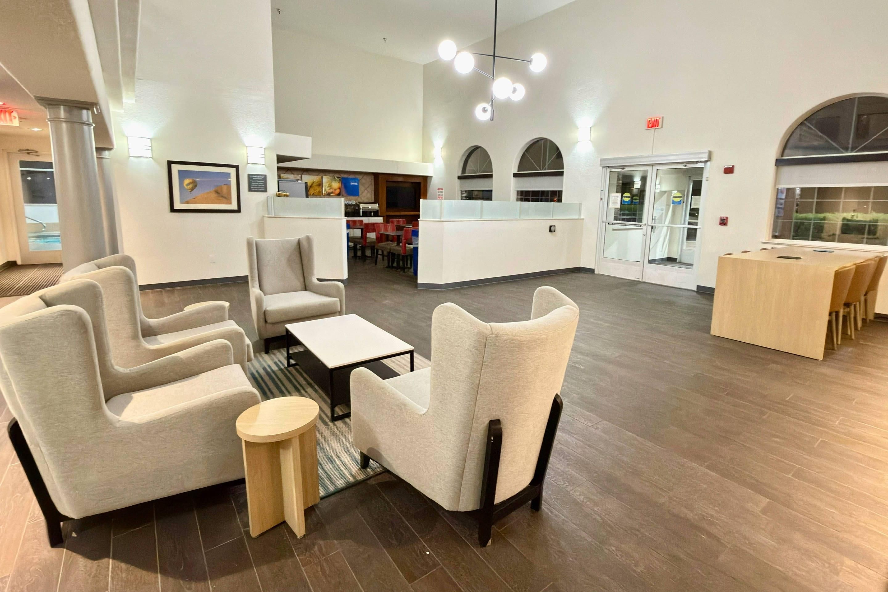 Um hall espaçoso com mobiliário moderno, um balcão de recepção e vista para a área da piscina.