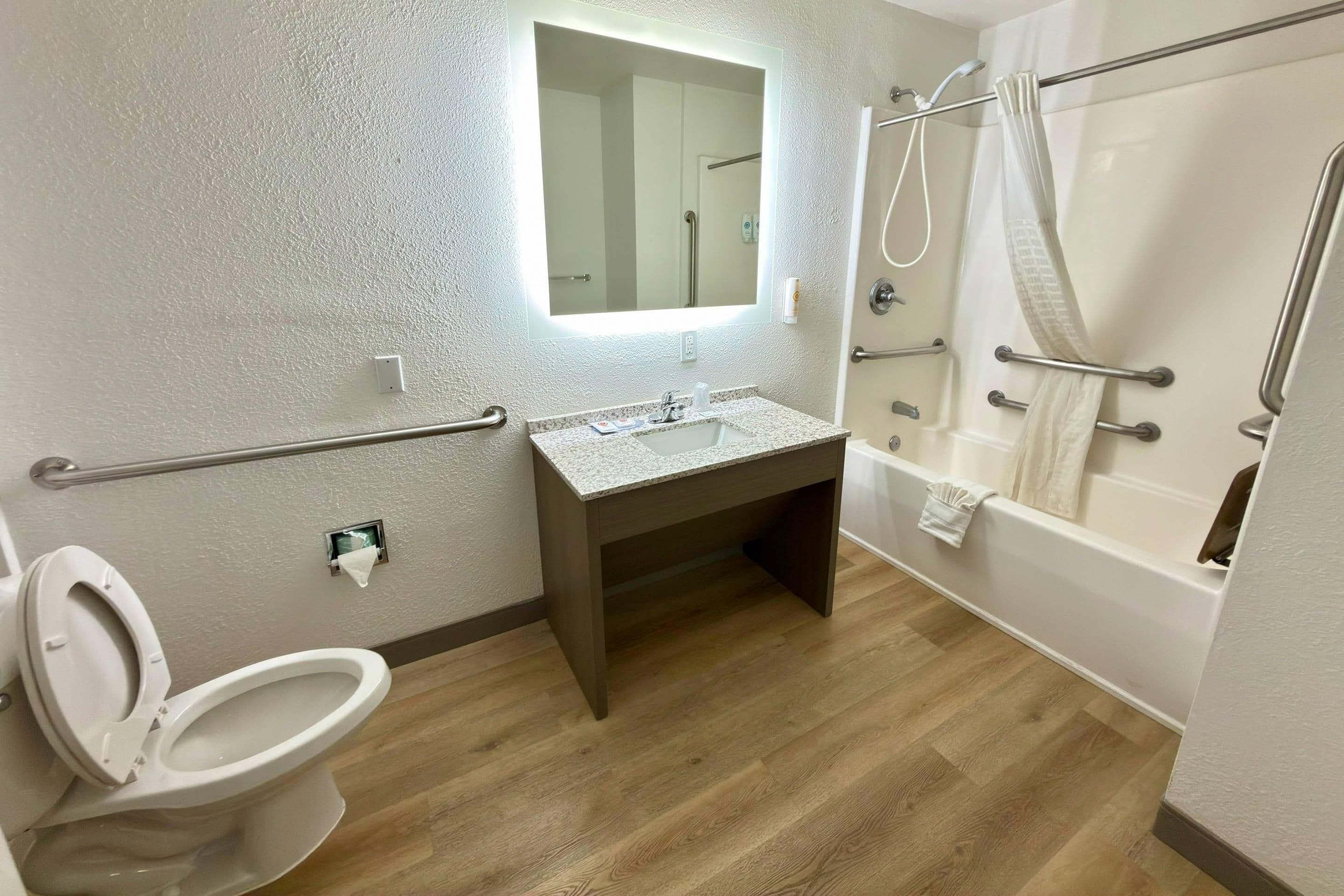 A bathroom with a toilet, sink, mirror, and shower area.