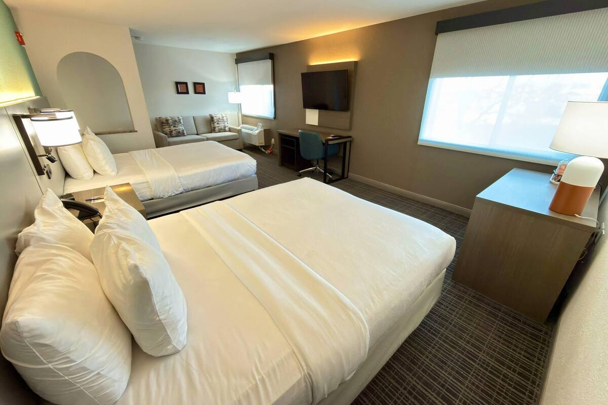 Hotellihuone, jossa on kaksi sänkyä, työpöytä, tuoli, televisio ja ikkuna.