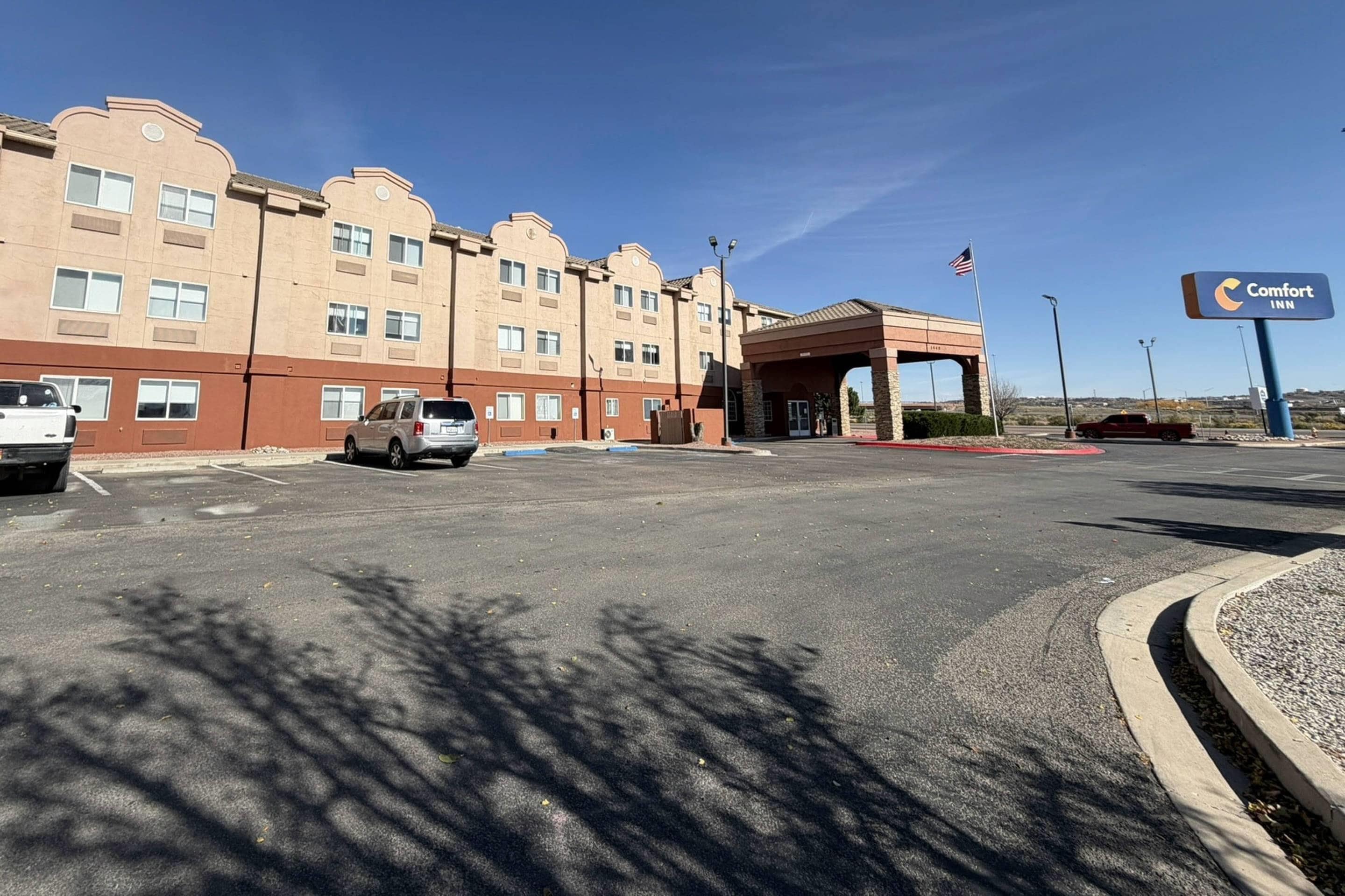 A Comfort Inn hotel with a parking lot, a building with multiple windows, and a flag.