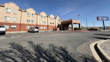 A Comfort Inn hotel with a parking lot, a building with multiple windows, and a flag.