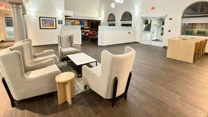 Eine geräumige Lobby mit modernen Möbeln, einer Rezeption und Blick auf den Poolbereich.