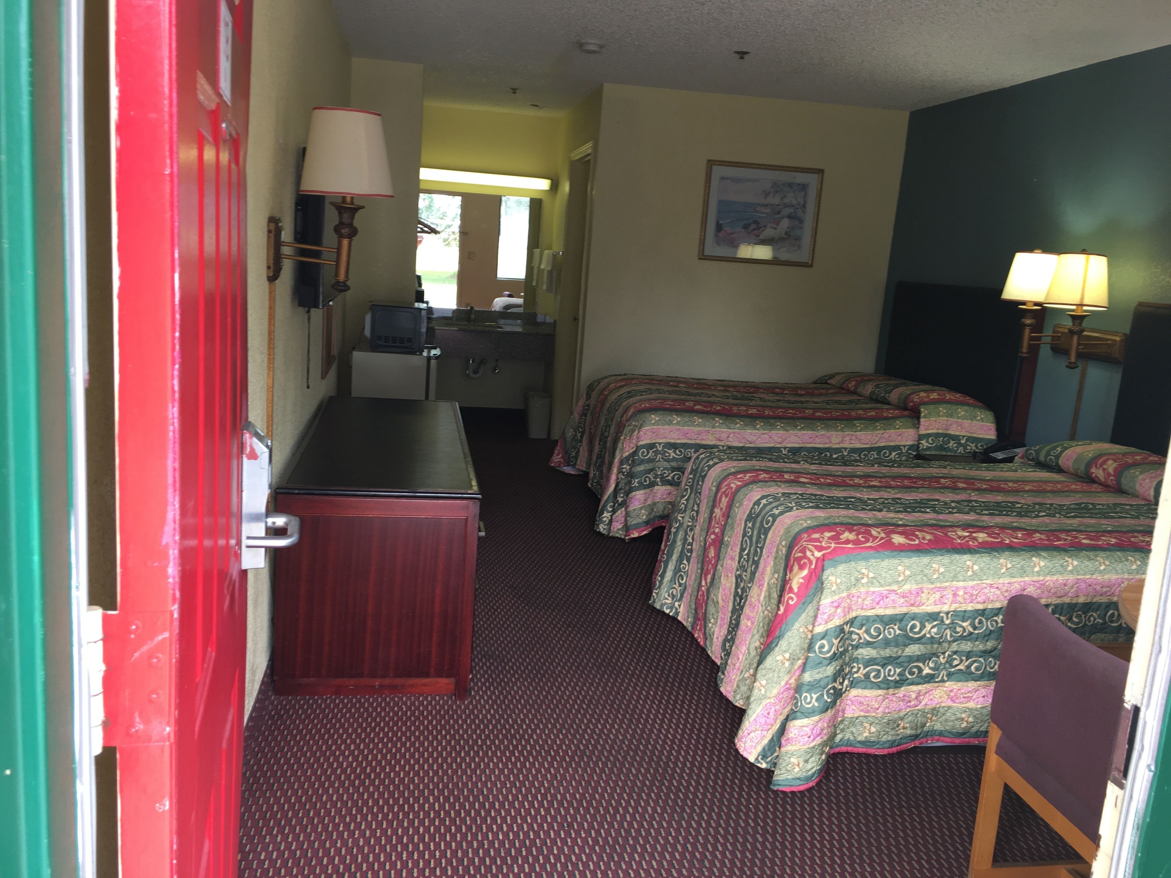 Habitación de hotel con dos camas, un escritorio, una silla y un aparador.