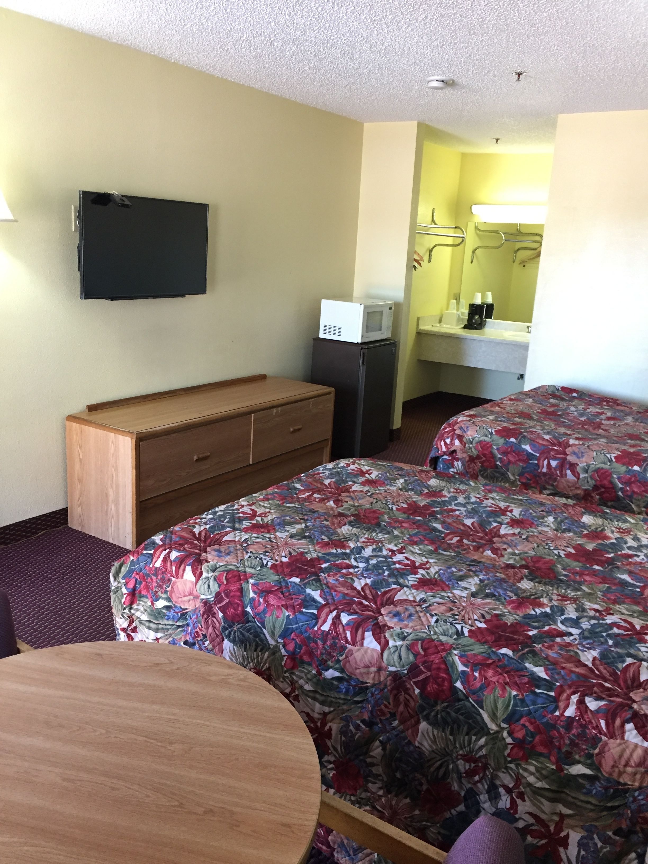 Habitación de hotel con cama, cómoda, escritorio, microondas y televisor.