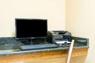 Una computadora de escritorio con monitor, teclado e impresora sobre una encimera de granito.
