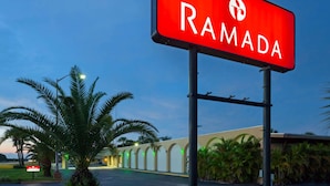 Um letreiro vermelho com a palavra "RAMADA" escrita, indicando um hotel ou resort.
