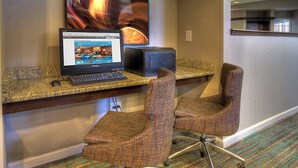 Un espace d’accueil d’hôtel comprenant un ordinateur de bureau, une imprimante et deux chaises de bureau.