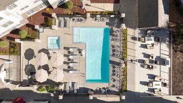 Relax by the rectangular pool surrounded by lounge chairs and umbrellas.