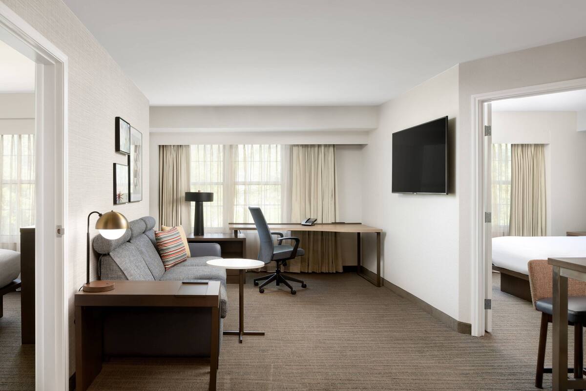 Habitación de hotel con cama, escritorio, silla, sofá y televisión.