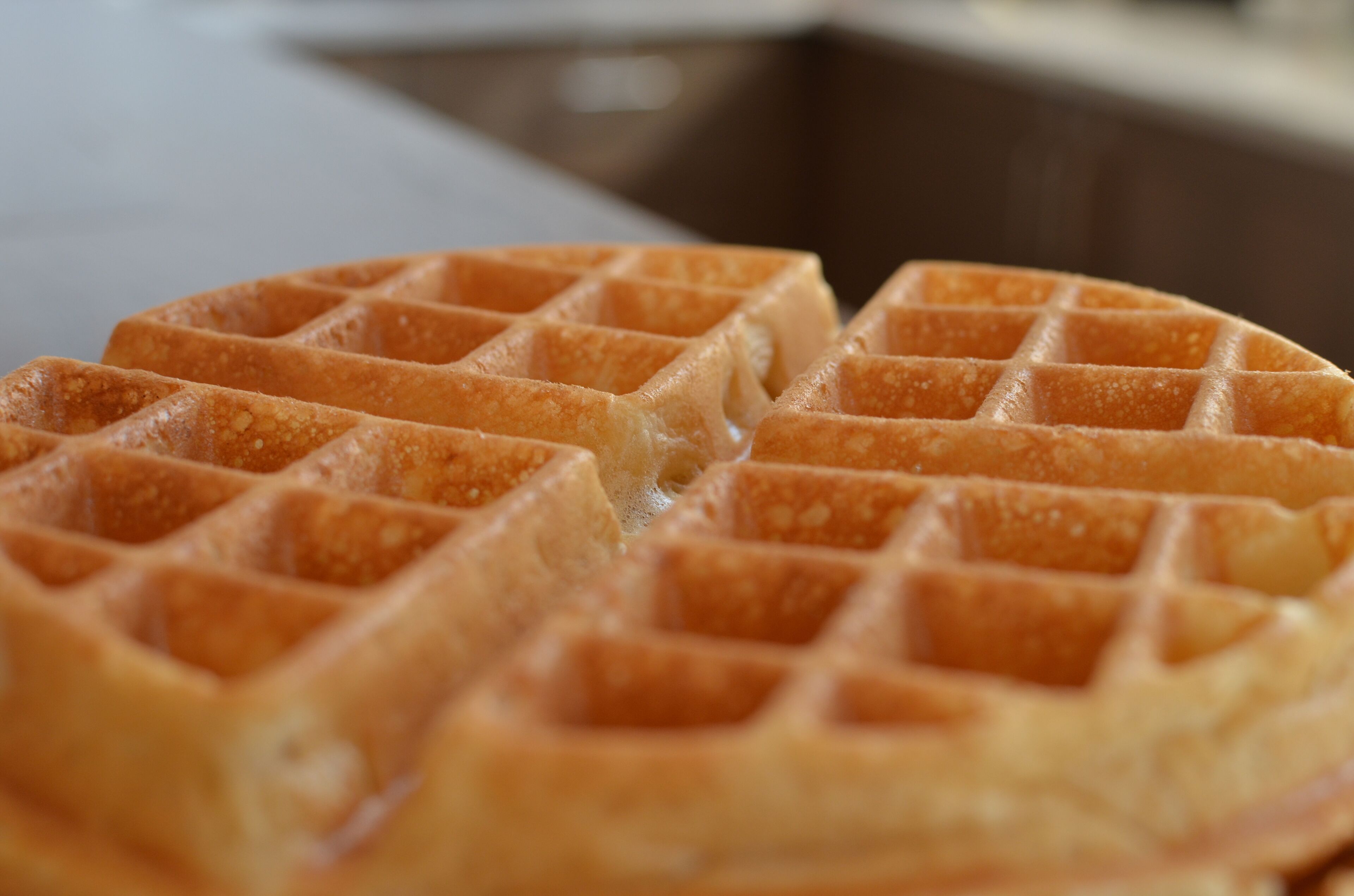 A close-up of a waffle with a golden-brown color and a grid pattern.